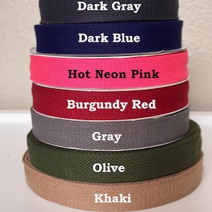 May include: A stack of seven rolls of woven cotton webbing tape in various colors, labeled with text: Dark Gray, Dark Blue, Hot Neon Pink, Burgundy Red, Gray, Olive, and Khaki. Each roll features a distinct twill texture and solid color.
