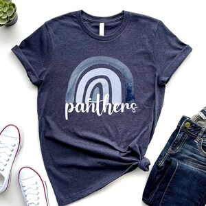 May include: A navy blue t-shirt with a watercolor rainbow design and the word "panthers" in white text.