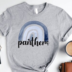 May include: A gray t-shirt with a blue watercolor rainbow and the word "panthers" in black lettering.