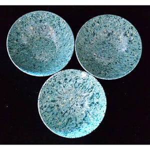 Op de afbeelding: Drie ronde kommen met een gespikkeld turquoise en wit patroon. De kommen zijn in een driehoekige formatie gerangschikt tegen een zwarte achtergrond. Het gespikkelde ontwerp geeft de kommen een unieke, handgemaakte uitstraling. Deze kommen zijn geschikt voor het serveren van voedsel.