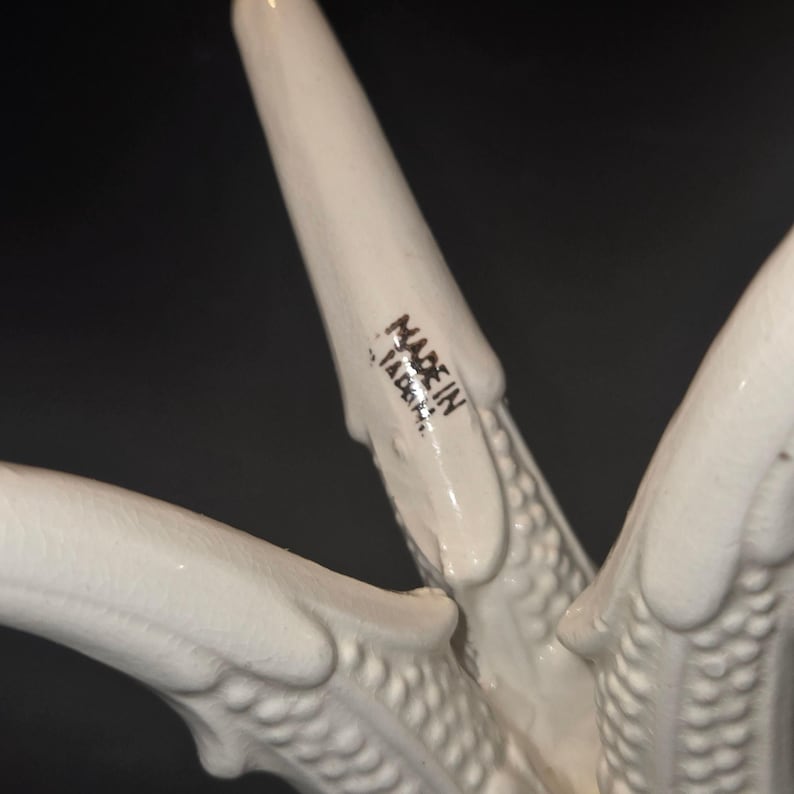 May include: Close-up of a white ceramic object with a textured surface. The object has multiple pointed projections. The words "MADE IN JAPAN" are printed in black on one of the projections.