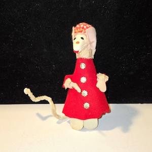 May include: A handmade mouse doll with a red felt dress adorned with gold sequins. The mouse has a white face, pink ears, and a red and white checkered hat. It has a long, curved, fuzzy tail and is made from wood and fabric.