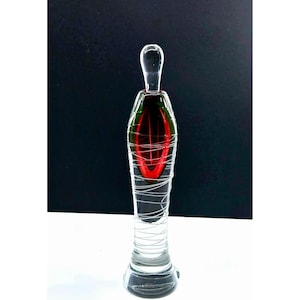 Puede incluir: Una botella de vidrio transparente con un diseño de vidrio rojo y verde. La botella tiene un cuello largo y delgado y una base redonda. La botella está decorada con un diseño de alambre plateado.