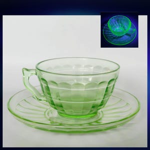 May include: A light green translucent glass teacup and saucer set featuring a scalloped rim design and horizontal ridges. An inset image shows the same glass teacup and saucer glowing with a bright neon green hue under ultraviolet light.