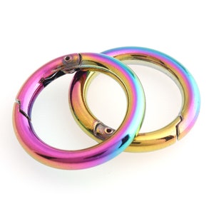 Peut inclure: Deux porte-clés métalliques arc-en-ciel avec un fermoir à ressort. Les anneaux sont entrelacés.