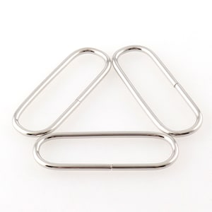 May include: Three silver metal oval rings, each with a different size. The rings are smooth and shiny.