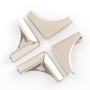 Könnte beinhalten: Vier silberfarbene Metalleckenschützer, kreisförmig angeordnet. Jeder Schutz hat ein gebogenes, abgewinkeltes Design mit flacher Oberseite und leicht erhöhtem Rand. Die Teile sind reflektierend und scheinen neu zu sein.