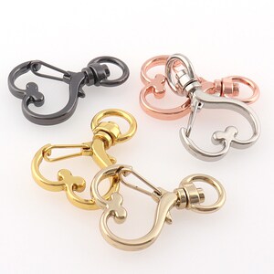 May include: Four heart-shaped swivel snap hooks in different finishes: black, rose gold, gold, and silver.