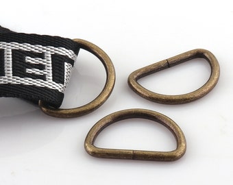 May include: Three antique gold-toned metal rings, two are D-shaped and one is a circle. The rings are used for attaching to straps or belts.