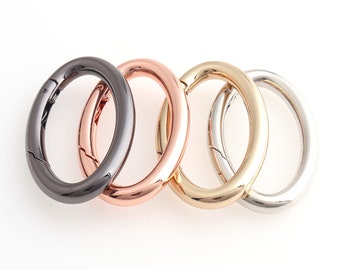 May include: Four metal key rings in different colors: black, rose gold, gold, and silver. The rings are oval shaped and have a spring-loaded clasp.