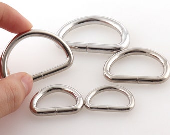 May include: Five silver metal D-rings of different sizes. The rings are smooth and shiny.