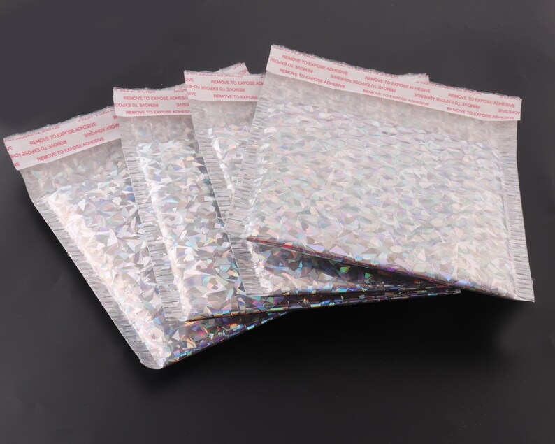 May include: Five silver iridescent padded mailing envelopes with a red warning label that reads "REMOVE TO EXPOSE ADHESIVE" on each envelope.