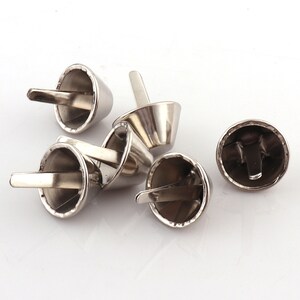 May include: Silver metal cone-shaped rivets with a flat base and a small metal loop on the top. The rivets are used for attaching fabric, leather, or other materials.