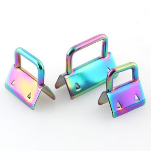 May include: Three iridescent metal D-ring buckles with a rainbow finish. The buckles are different sizes and have a triangular shape.