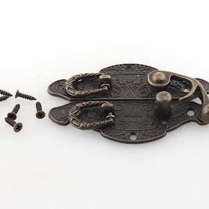 May include: Antique bronze latch with ornate design and two decorative handles. The latch has a hook and a small knob. It comes with eight screws.