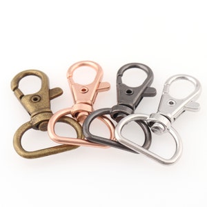 Puede incluir: Cuatro cierres giratorios de metal en latón antiguo, cobre, metal de cañón y plata. Cada cierre tiene un gancho de mosquetón y una anilla en D. Ideales para llaveros, cordones y accesorios de bolsos.