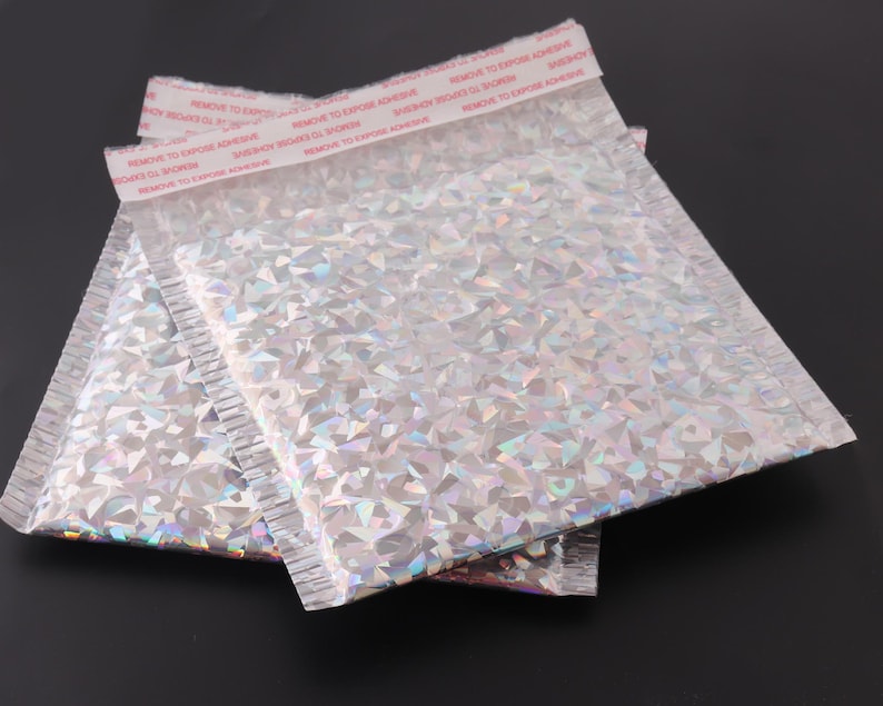 May include: Two silver iridescent padded mailing envelopes with a red adhesive strip that reads "REMOVE TO EXPOSE ADHESIVE".