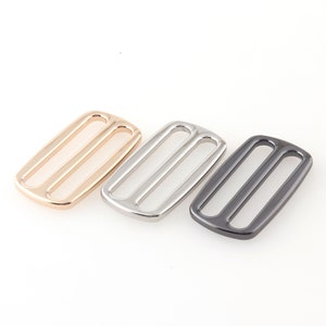 May include: Three metal slider buckles in gold, silver, and black.