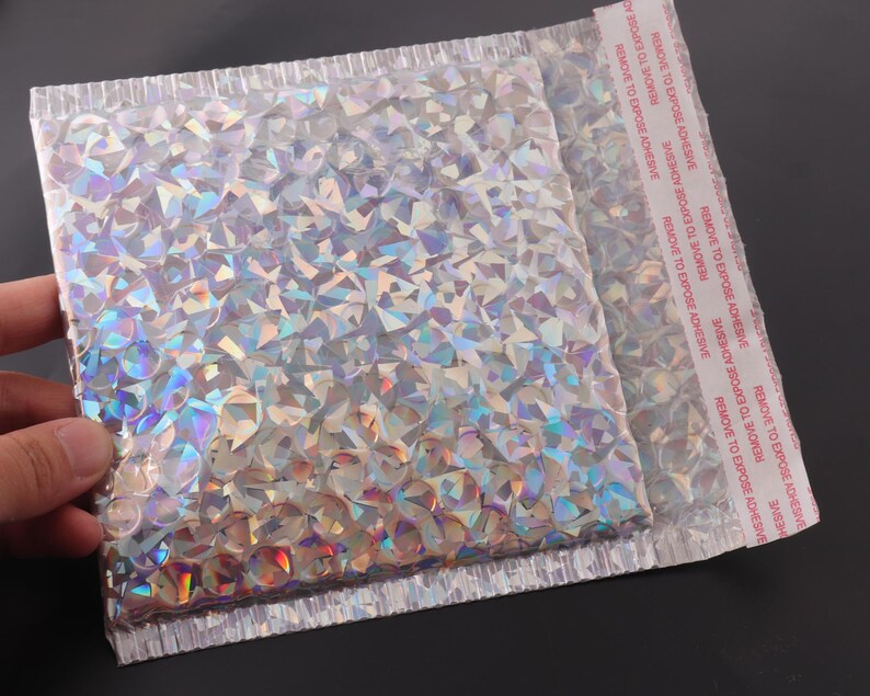 May include: A silver iridescent padded envelope with a red "REMOVE TO EXPOSE ADHESIVE" label on the side.