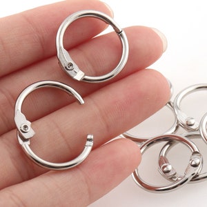 May include: Silver metal key rings with a spring-loaded opening mechanism. The rings are in various sizes and are ideal for attaching keys, charms, or other small items.