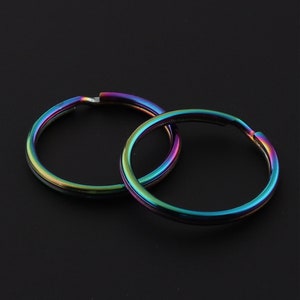 May include: Two iridescent key rings, one overlapping the other, against a black background.
