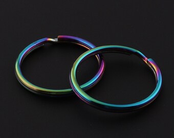May include: Two iridescent key rings, one overlapping the other, against a black background.