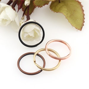 May include: Three key rings in different colors: black, bronze, and rose gold. The key rings are all the same size and are made of metal.