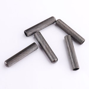 May include: Five silver metal cord ends with a twisted design. The cord ends are about 1 inch long.