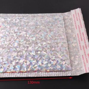 May include: A silver iridescent padded mailing envelope with a peel-and-seal adhesive strip. The envelope measures 130mm by 150mm.