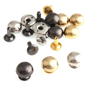 May include: Assortment of metal rivets in gold, silver, and black. The rivets are in various sizes and shapes, with some having a domed top and others having a flat top.