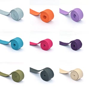 Puede incluir: Nueve rollos de cincha de colores en varios tonos, incluyendo azul, naranja, morado, turquesa, rosa y verde. Cada rollo está bien enrollado, con el extremo de la cincha extendiéndose hacia afuera. El fondo es blanco liso.