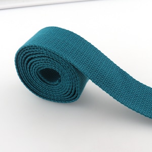 May include: A teal blue cotton webbing strap rolled up. The strap is about 1 inch wide.