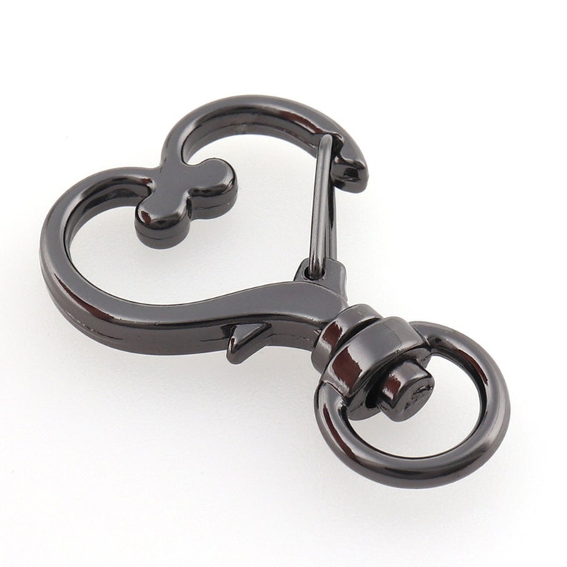 May include: Black metal heart-shaped swivel clasp with a spring-loaded gate. The clasp has a round ring on one side and a heart-shaped loop on the other.