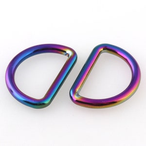 May include: Two iridescent rainbow colored metal D-rings. The rings are smooth and shiny.