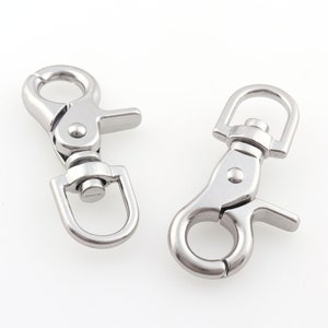 May include: Two silver metal swivel snap hooks. The hooks have a D-ring on one end and a spring-loaded clasp on the other end.
