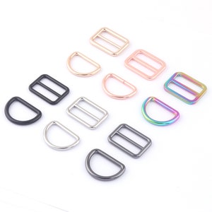 May include: Assortment of metal D-rings and slider buckles in various finishes, including black, silver, gold, rose gold, and rainbow.