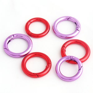 May include: Six metal key rings in two colors: purple and red. The rings are open and ready to be attached to keys, bags, or other items.