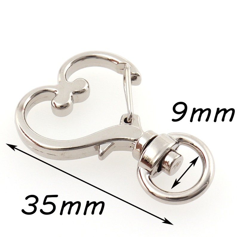 May include: Silver heart-shaped swivel clasp with a 9 mm diameter ring and a 35 mm length. The clasp is designed for attaching to a keychain, bag, or other items.