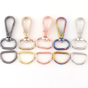 May include: Five different colored metal swivel clasps with D-rings. The clasps are in black, gold, rose gold, rainbow, and silver.