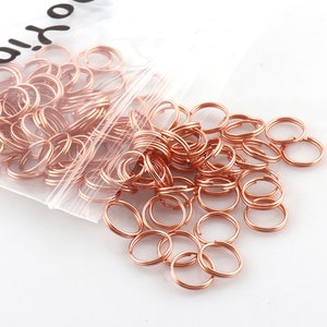May include: A clear plastic bag filled with a large quantity of small, rose gold jump rings. The bag is labeled "Onyx".