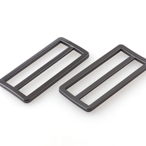 May include: Two black metal slider buckles. The buckles are rectangular with a smooth finish.