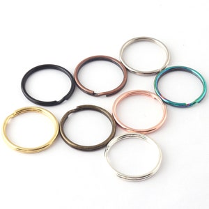 May include: Assortment of eight key rings in various colors and finishes, including silver, gold, black, copper, and iridescent green.