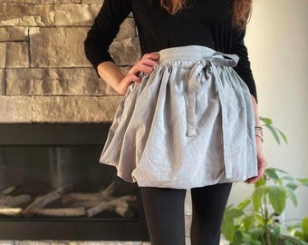 May include: A gray linen apron with a gathered skirt and a tie at the waist.