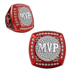 May include: Two red rings with the text "MVP". The rings have a square shape with a circle in the center. The center circle is filled with small, clear stones. The rings are surrounded by clear stones.