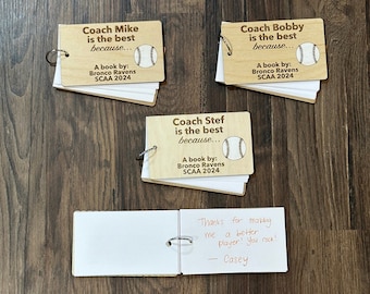 Puede incluir: Tres cuadernos de madera con temática de béisbol con el texto "Coach Mike is the best because... A book by: Bronco Ravens SCAA 2024", "Coach Bobby is the best because... A book by: Bronco Ravens SCAA 2024" y "Coach Stef is the best because... A book by: Bronco Ravens SCAA 2024". También se muestra un pequeño cuaderno blanco con el texto "Thanks for making me a better player! You rock! - Casey".