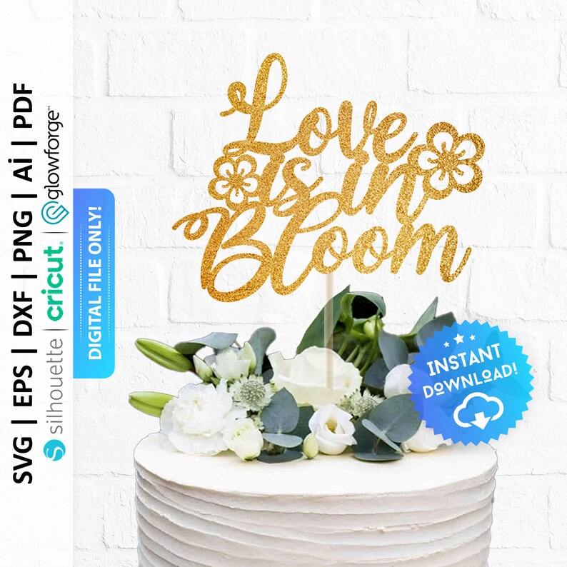 May include: Gold glitter cake topper with the text "Love is in Bloom" and two small flower designs. The topper is on a white cake with white flowers.