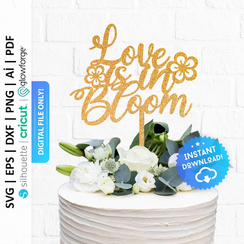 May include: Gold glitter cake topper with the text "Love is in Bloom" and two small flower designs. The topper is on a white cake with white flowers.