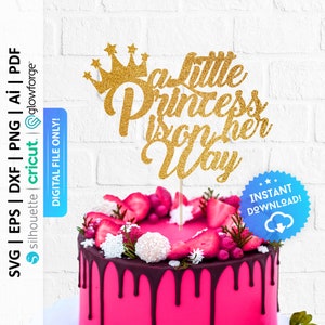 Op de afbeelding: Een gouden glittertaarttopper met een kroon en de tekst "A Little Princess is on her Way".