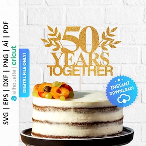 Pode incluir: Topper de bolo de glitter dourado com o texto "50 anos juntos" e detalhes de folhas. O topper est&aacute; em cima de um bolo branco com frutas.
