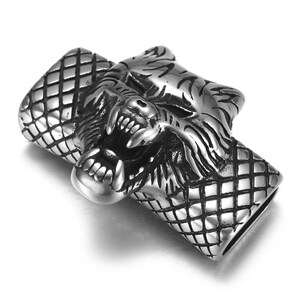 May include: Silver-toned metal wolf head charm with a textured design. The wolf's mouth is open and its teeth are visible. The charm is attached to a chain.